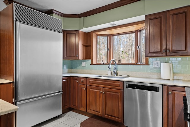 kitchen with crown molding, light countertops, appliances with stainless steel finishes, light tile patterned flooring, and a sink