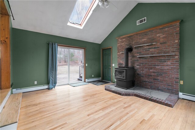 unfurnished living room featuring a wood stove, a baseboard radiator, and visible vents