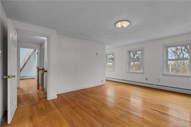 unfurnished room featuring light wood-style floors, a baseboard radiator, and baseboards