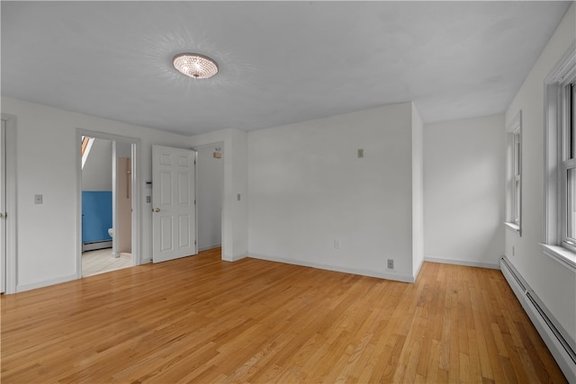 spare room featuring light wood finished floors, baseboards, and a baseboard heating unit