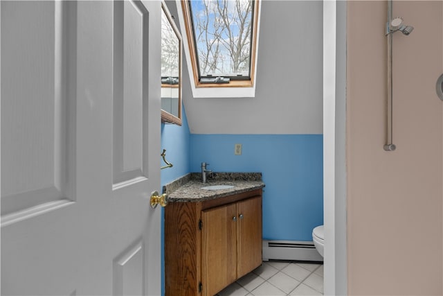 bathroom featuring tile patterned flooring, toilet, a skylight, vanity, and baseboard heating