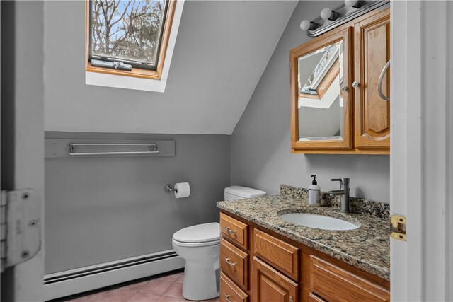 bathroom featuring toilet, a baseboard heating unit, lofted ceiling with skylight, vanity, and tile patterned floors