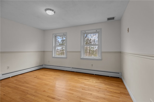 spare room with light wood-type flooring, visible vents, and baseboard heating