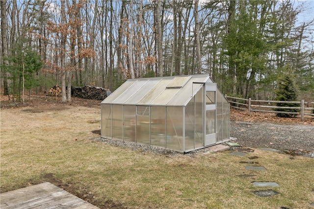 view of greenhouse featuring fence and a lawn