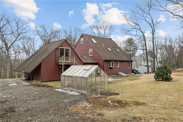 back of property with a shingled roof, an exterior structure, a yard, and an outdoor structure