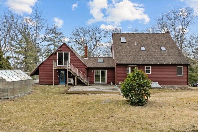 back of property with a lawn, a chimney, an outbuilding, a deck, and an exterior structure