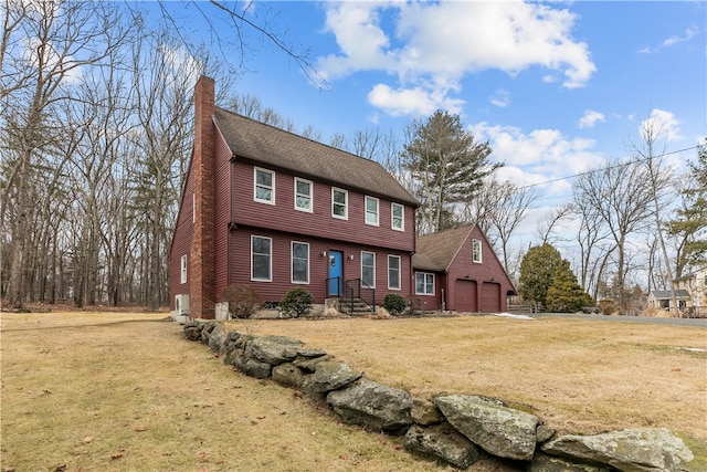 colonial house featuring a front yard, roof with shingles, a chimney, and an attached garage