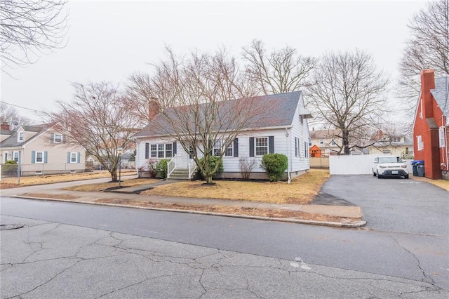 view of front of property with entry steps, a chimney, fence, and aphalt driveway