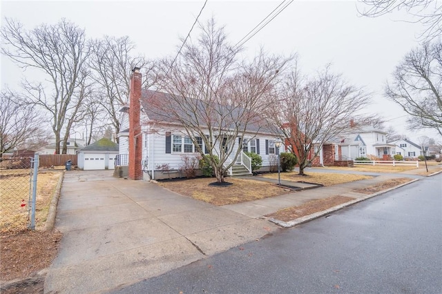 view of front of home with an outbuilding, fence, driveway, a residential view, and a chimney