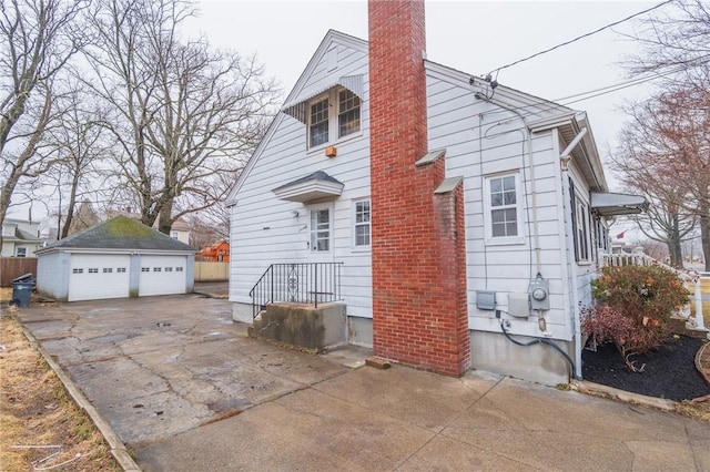 view of side of home featuring a garage, an outdoor structure, and a chimney