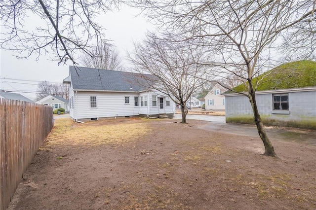 back of property with a shingled roof and fence