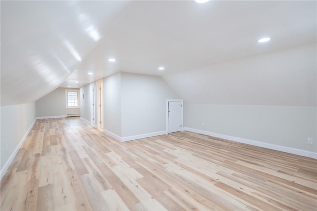 bonus room with a baseboard heating unit, lofted ceiling, baseboards, and light wood finished floors