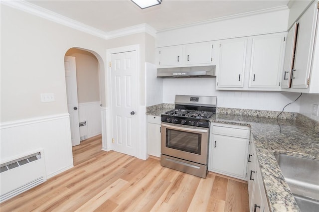 kitchen with arched walkways, light wood-style floors, ornamental molding, gas range, and under cabinet range hood