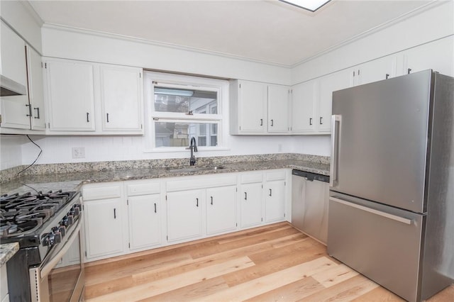 kitchen featuring appliances with stainless steel finishes, light stone countertops, light wood-style floors, white cabinetry, and a sink