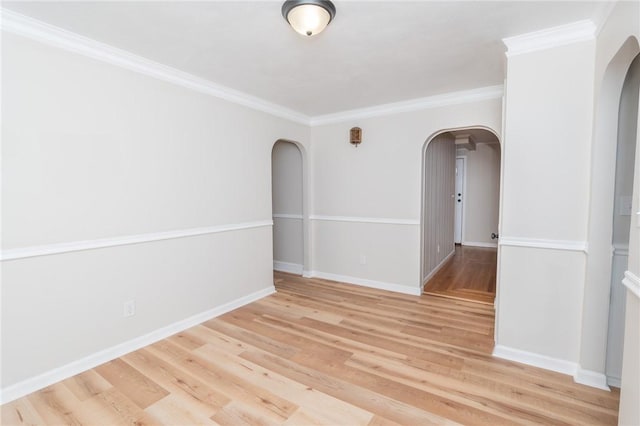 spare room featuring arched walkways, wood finished floors, and baseboards