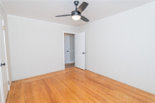 empty room featuring crown molding, light wood finished floors, and ceiling fan