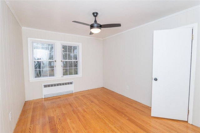 empty room featuring ornamental molding, light wood-style flooring, radiator heating unit, and a ceiling fan