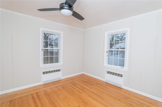 spare room featuring light wood-style floors, radiator, and ornamental molding