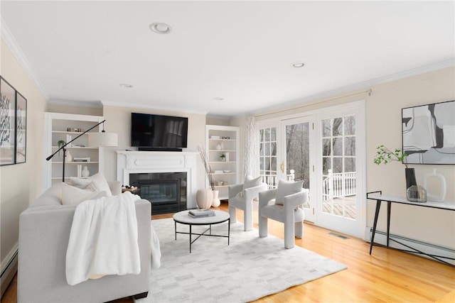 living room featuring a fireplace with flush hearth, wood finished floors, visible vents, baseboard heating, and crown molding