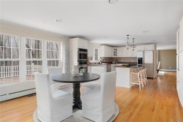 dining area with a chandelier, a baseboard heating unit, recessed lighting, and light wood-style floors