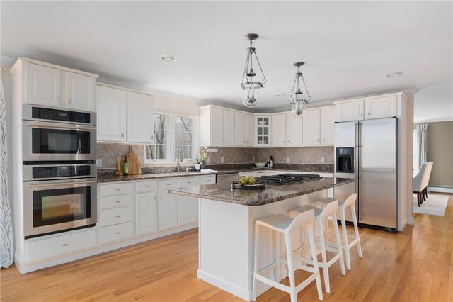 kitchen featuring white cabinets, light wood-style flooring, stainless steel appliances, and a sink