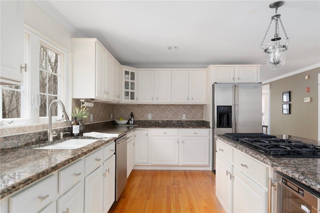 kitchen with stainless steel appliances, decorative backsplash, a sink, and crown molding