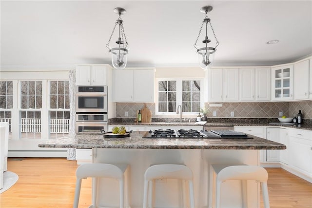 kitchen with stainless steel appliances, white cabinets, decorative backsplash, and a kitchen bar