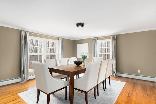 dining space with light wood-type flooring, baseboards, a baseboard heating unit, and crown molding