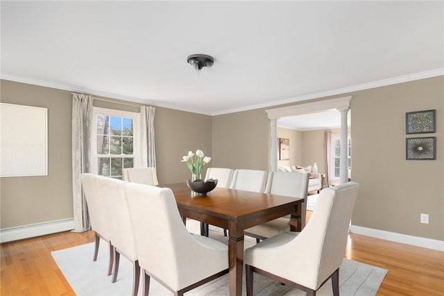 dining space with baseboards, light wood finished floors, a baseboard radiator, and ornate columns