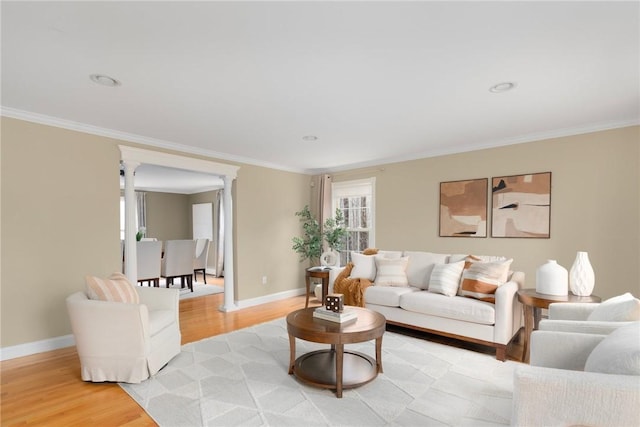 living area featuring baseboards, light wood-type flooring, and crown molding