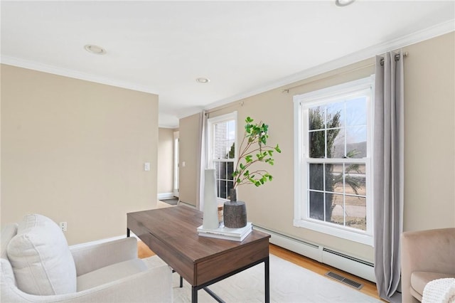 office area with a baseboard heating unit, visible vents, crown molding, and light wood-style flooring