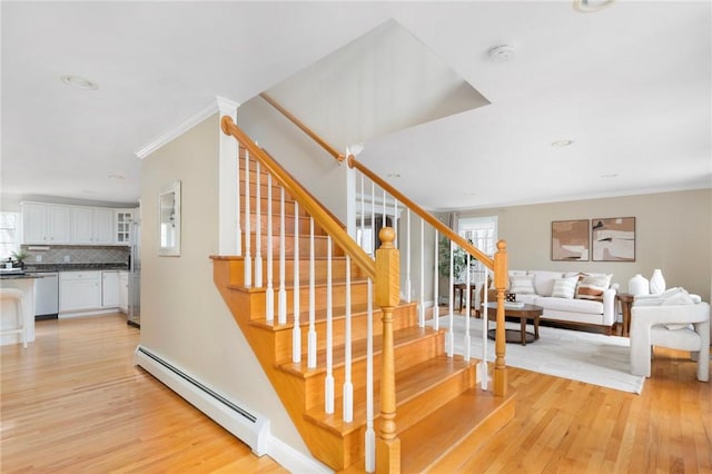 stairs featuring a baseboard radiator, crown molding, and wood finished floors