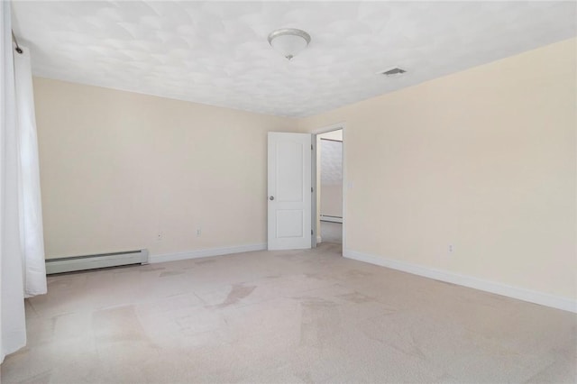 empty room featuring light carpet, baseboard heating, visible vents, and baseboards