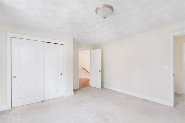 unfurnished bedroom featuring a closet, light colored carpet, and baseboards