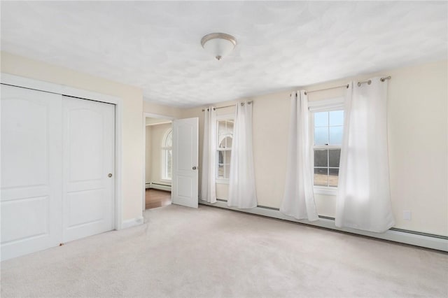 unfurnished bedroom with a baseboard radiator, a closet, and carpet flooring