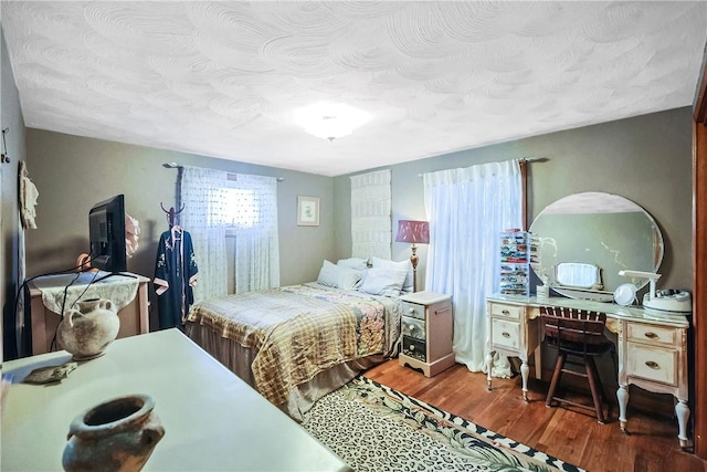 bedroom with a textured ceiling and wood finished floors