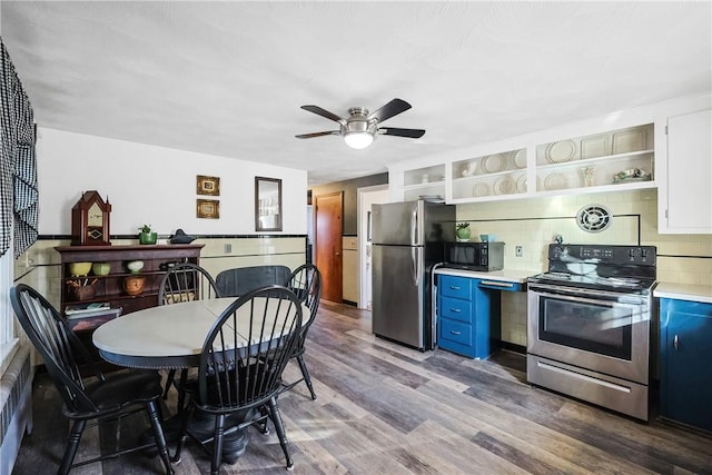 kitchen with appliances with stainless steel finishes, wood finished floors, blue cabinets, light countertops, and open shelves