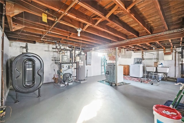 basement with gas water heater, a sink, electric panel, a heating unit, and washing machine and clothes dryer