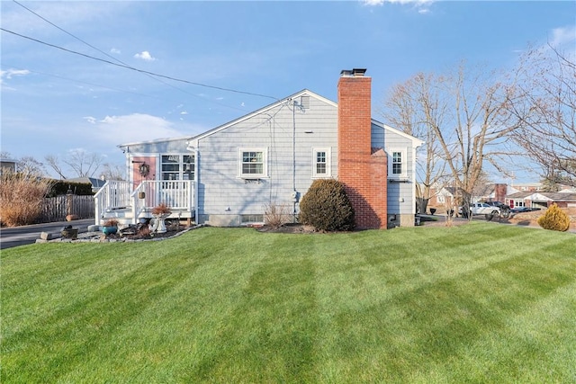 back of house with a chimney and a yard