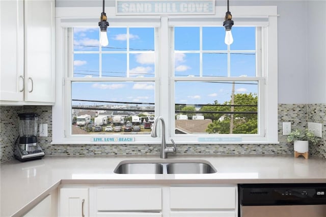 kitchen with dishwasher, backsplash, light countertops, white cabinetry, and a sink