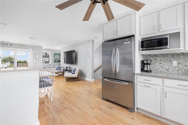 kitchen featuring white cabinetry, light countertops, appliances with stainless steel finishes, decorative backsplash, and light wood finished floors