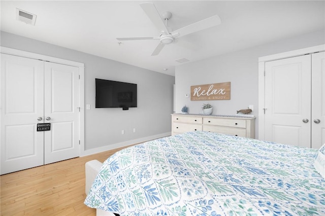 bedroom featuring light wood finished floors, baseboards, visible vents, a ceiling fan, and two closets