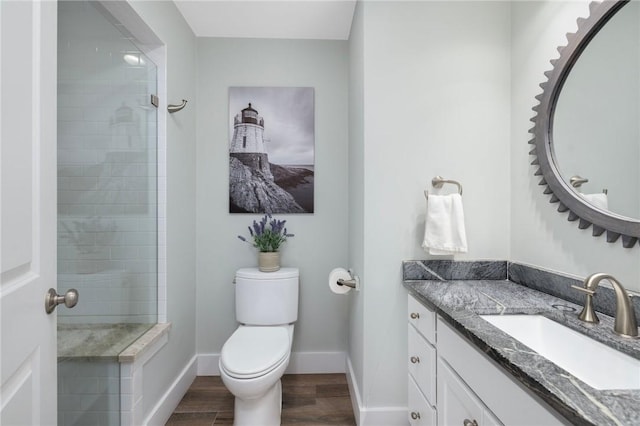 bathroom featuring vanity, baseboards, wood finished floors, and tiled shower