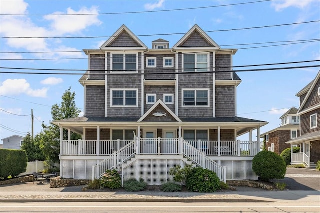 shingle-style home featuring covered porch and stairway