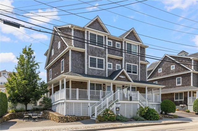 shingle-style home featuring covered porch and stairway