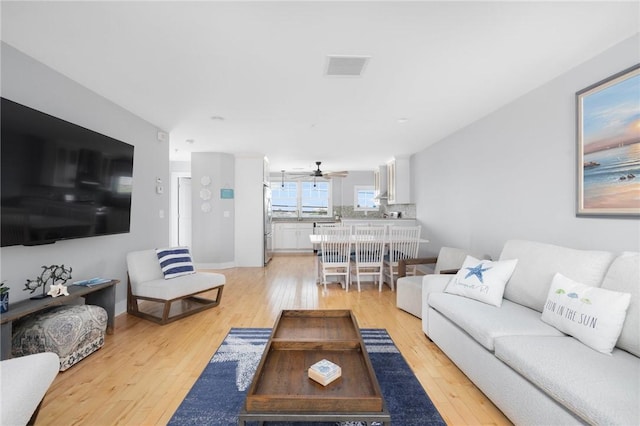 living room featuring light wood finished floors, ceiling fan, and visible vents