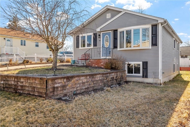 bungalow-style home with a front lawn and fence