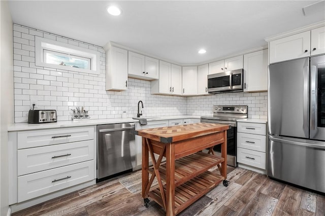 kitchen with decorative backsplash, dark wood-type flooring, stainless steel appliances, light countertops, and a sink