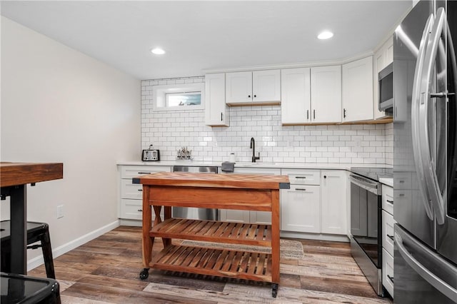 kitchen with tasteful backsplash, dark wood finished floors, stainless steel appliances, light countertops, and a sink