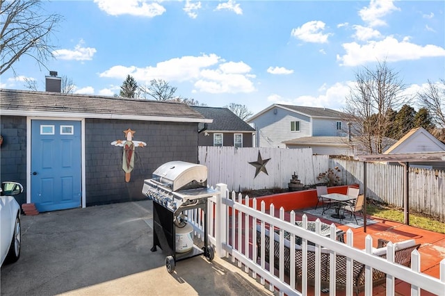 view of patio featuring outdoor dining space, a fenced backyard, an outbuilding, and area for grilling